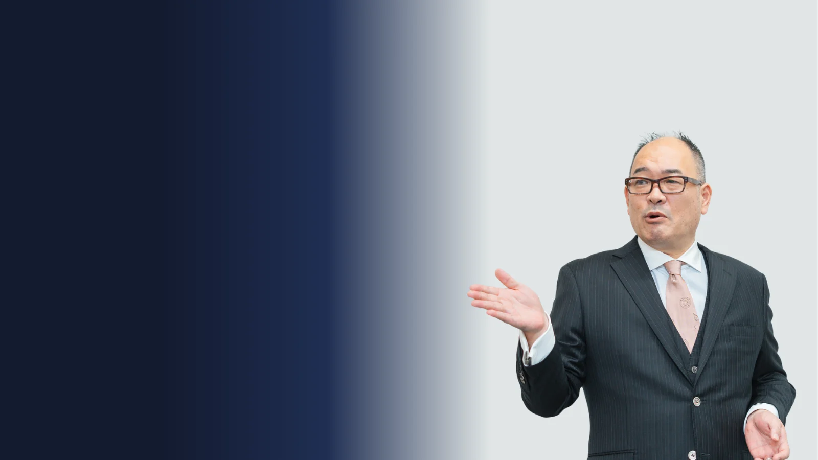 ミューコネクト株式会社 代表取締役社長 横井むつとも（婚活参謀★むつとも）― ピンストライプのスーツで手を差し出して語りかける写真